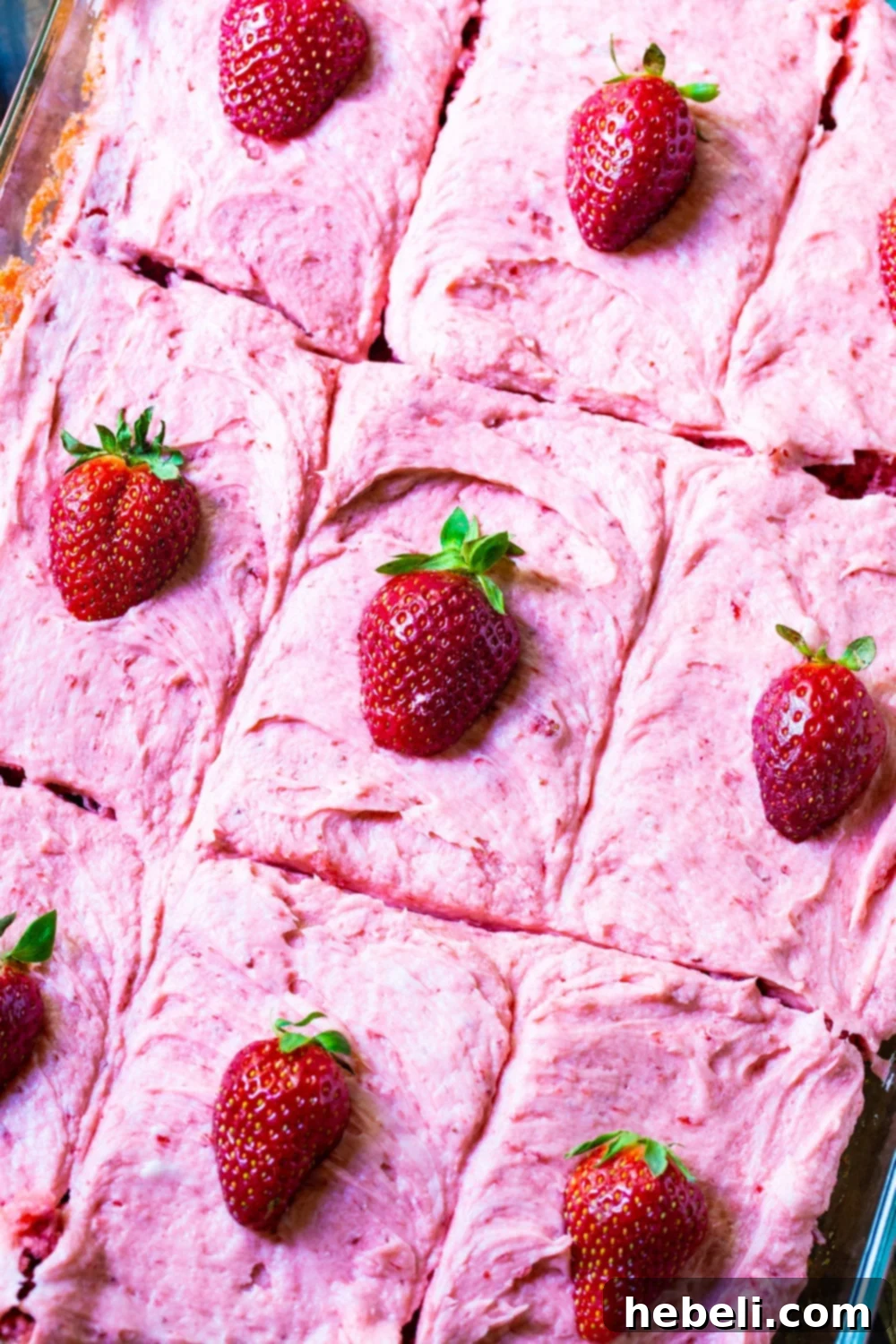 Perfect Strawberry Sheet Cake 4 Close-up shot of a Strawberry Sheet Cake in a baking pan, with several squares individually topped with fresh strawberry halves for an inviting presentation.