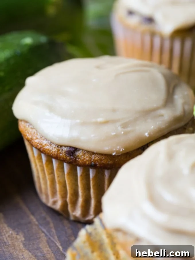 Close-up of a fluffy Zucchini Cupcake topped with shiny, rich Caramel Frosting and subtle chocolate chips