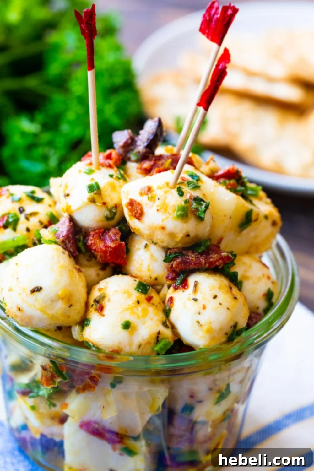 Close-up of spicy marinated mozzarella balls with toothpicks, garnished with fresh herbs, ready to be picked up.