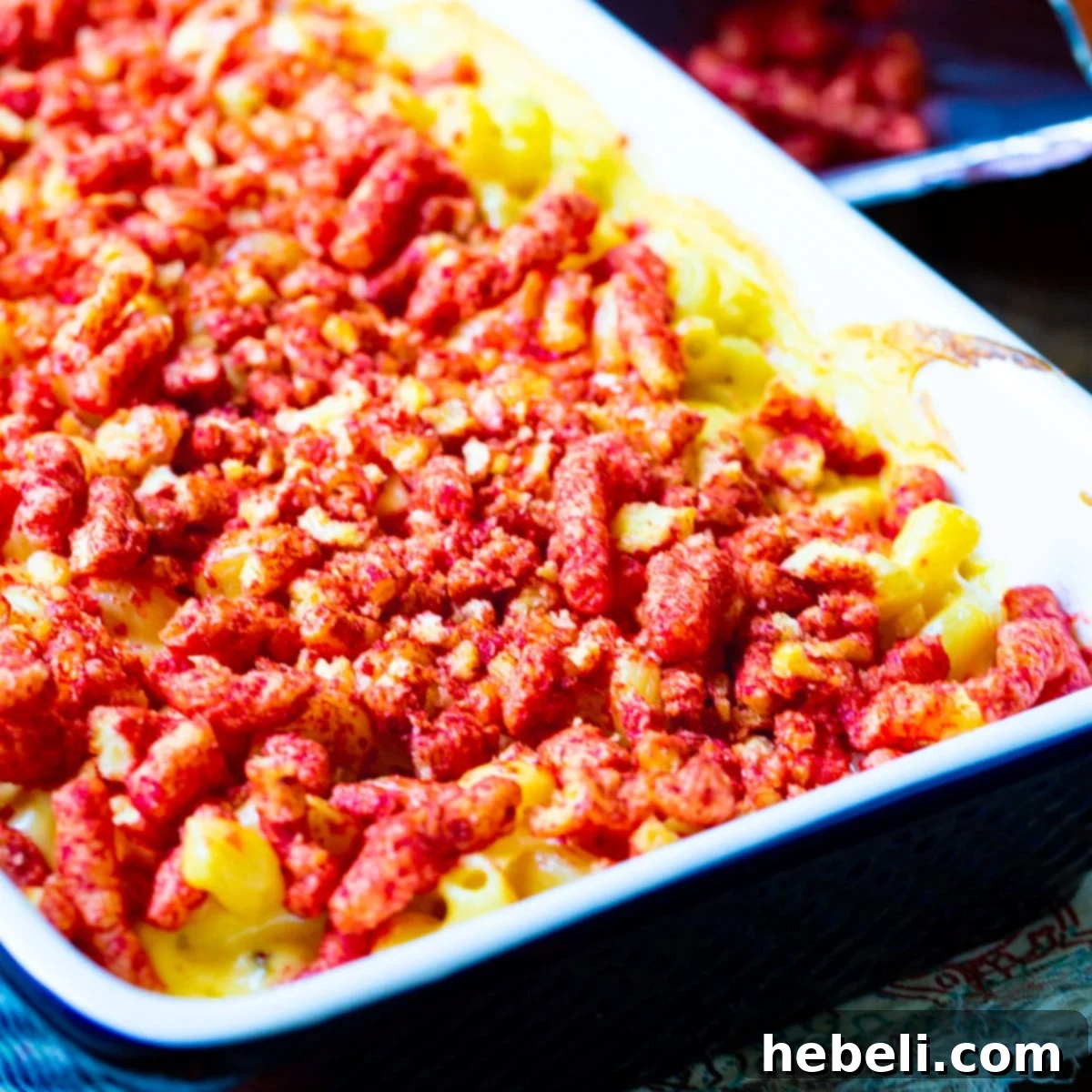 A large baking dish filled with bubbling Flamin' Hot Cheetos Mac and Cheese, garnished with fresh herbs.