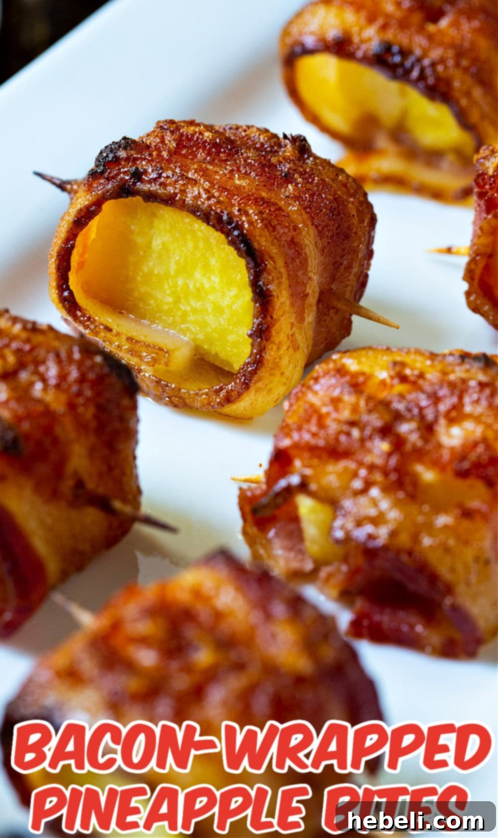 A generous pile of freshly baked Spicy Bacon Wrapped Pineapple Bites on a large serving tray.