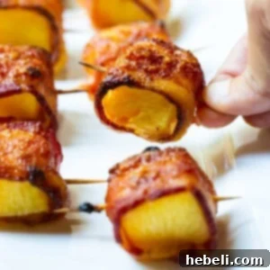 A dish of freshly prepared Spicy Bacon Wrapped Pineapple Bites, highlighting the glazed and crispy bacon.