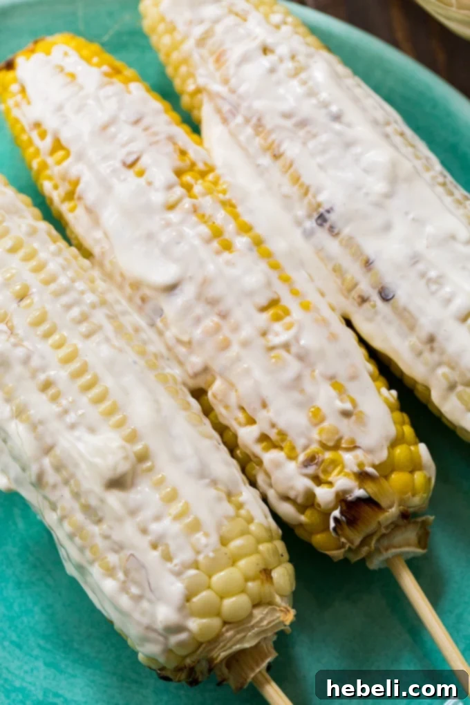 Close-up of a perfectly grilled ear of corn coated in a creamy sauce and Flamin' Hot Cheetos