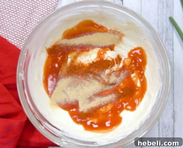 Adding hot sauce, honey, cayenne pepper, and garlic powder to the cream cheese mixture.