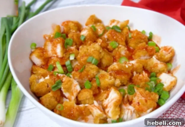 Garnishing the Nashville Hot Chicken Dip with sliced green onions.