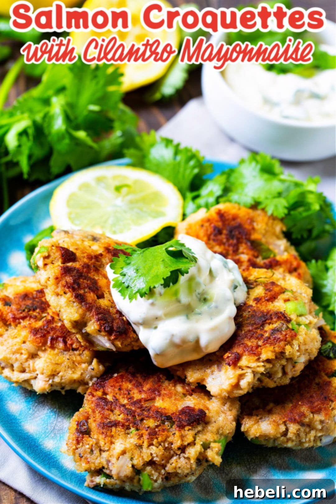 Close-up of three golden-fried Salmon Croquettes with Cilantro Mayonnaise, garnished with fresh cilantro sprigs, on a serving plate.
