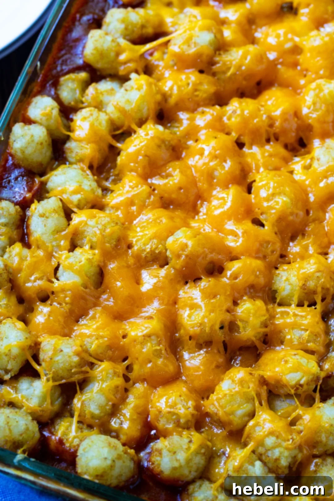 Tater Tot Casserole baking in a 9x13 inch dish, covered with cheese and tater tots.