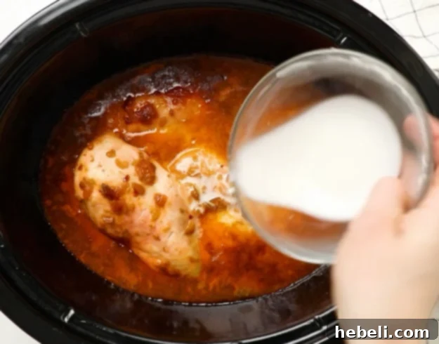 Adding cornstarch mixture to thicken the sauce in the slow cooker.