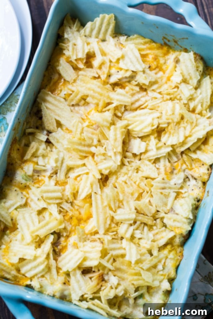 Warm Chicken Salad Bake 3 An old-fashioned Hot Chicken Salad casserole, freshly baked with a golden, crispy topping, sitting in a ceramic dish on a rustic wooden surface.