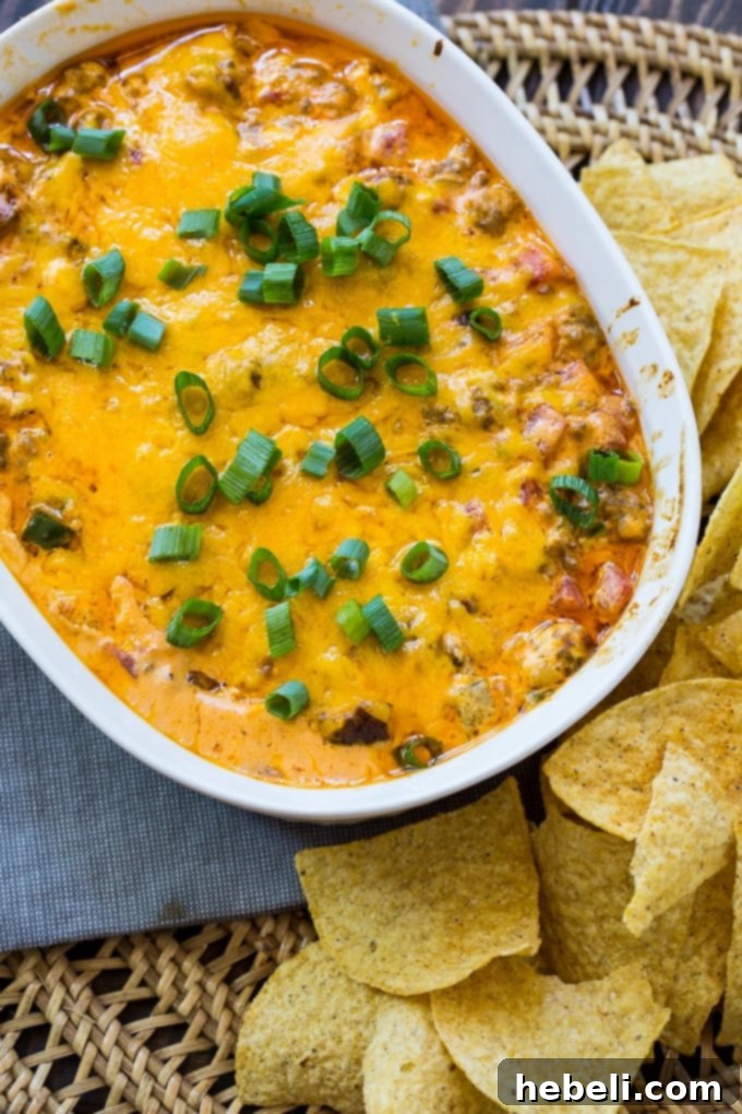 Close-up of a serving spoon scooping out a portion of the hot and gooey Spicy Sausage Cheese Dip, showcasing its rich texture and melted cheese.