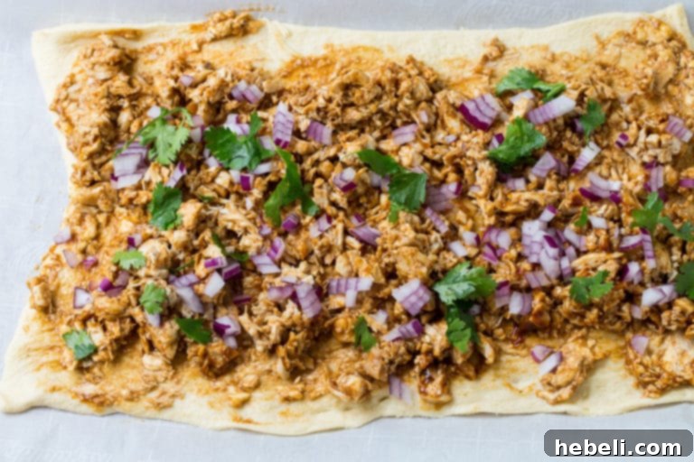 Spreading cream cheese and BBQ sauce mixture evenly over crescent roll dough.