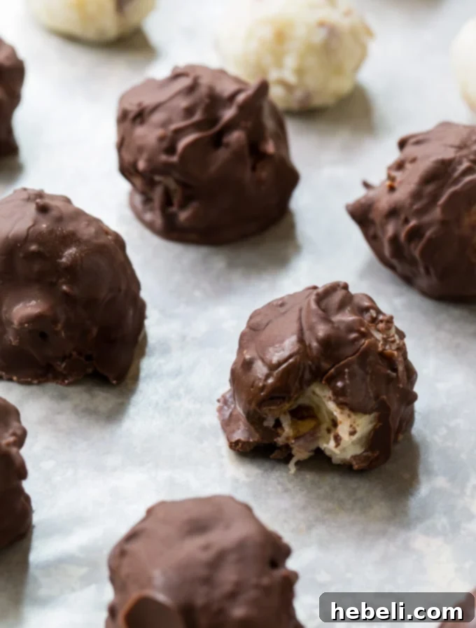 A close-up of Martha Washington Candies on a baking sheet, some fully dipped in chocolate, others partially, showing the smooth, rich coating.