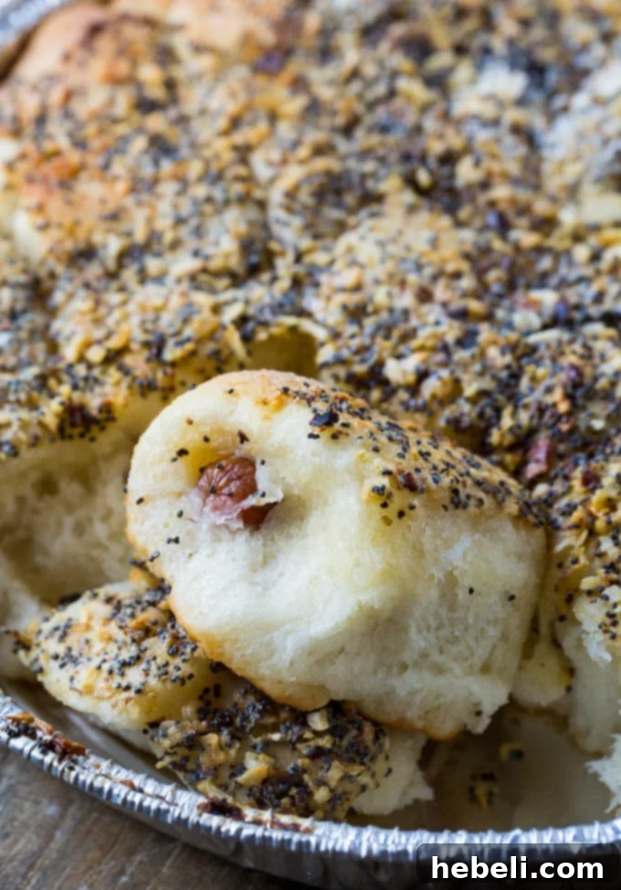 A freshly baked Poppy Seed Sausage Roll in hand, showing the delicious buttery topping.