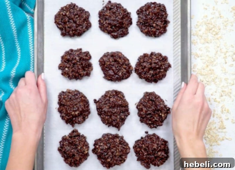 Freshly formed No-Bake Chocolate Oatmeal Cookies cooling and setting on a baking sheet lined with parchment paper.