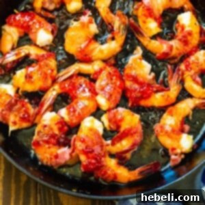 Bacon-Wrapped Shrimp with Pepper Jelly Glaze in a cast iron pan.