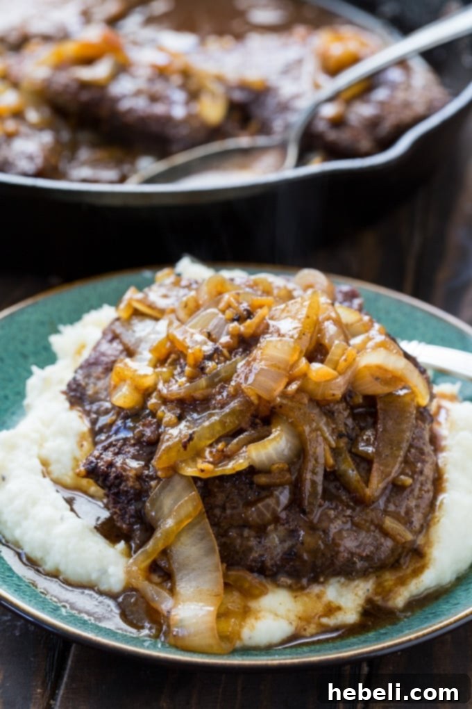 Smothered Steak Bites with Golden Onion Gravy 10 A hearty serving of cubed steak and rich onion gravy over mashed potatoes, embodying classic Southern comfort food.