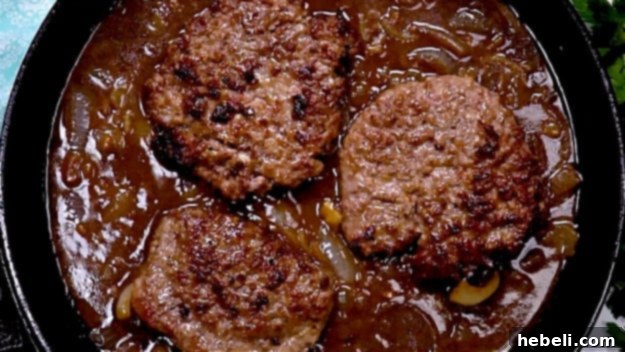 Smothered Steak Bites with Golden Onion Gravy 9 Cooked cubed steaks being placed back into a skillet filled with rich onion gravy to warm.