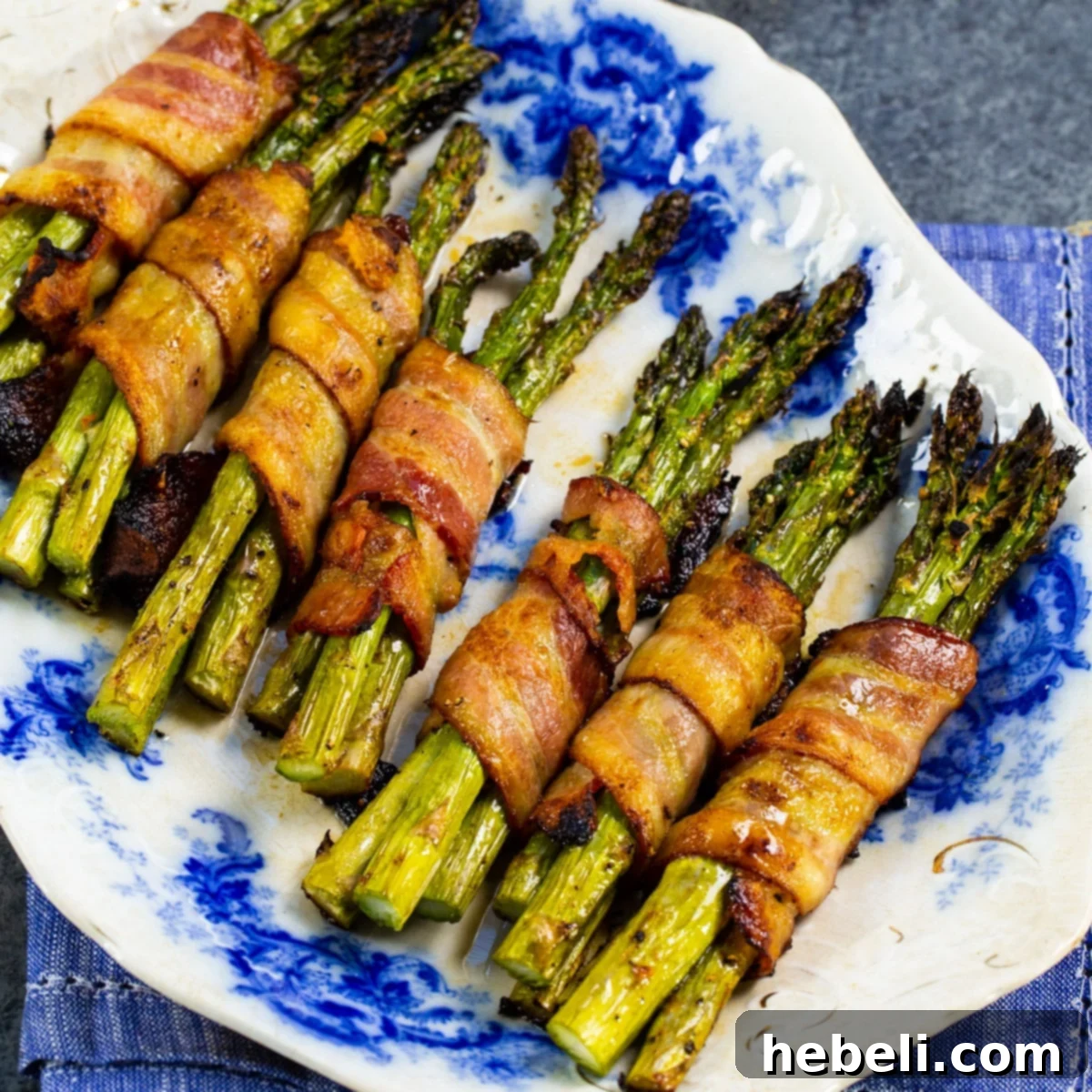 Bacon Wrapped Asparagus Bundles beautifully arranged on a white serving plate, garnished for presentation.