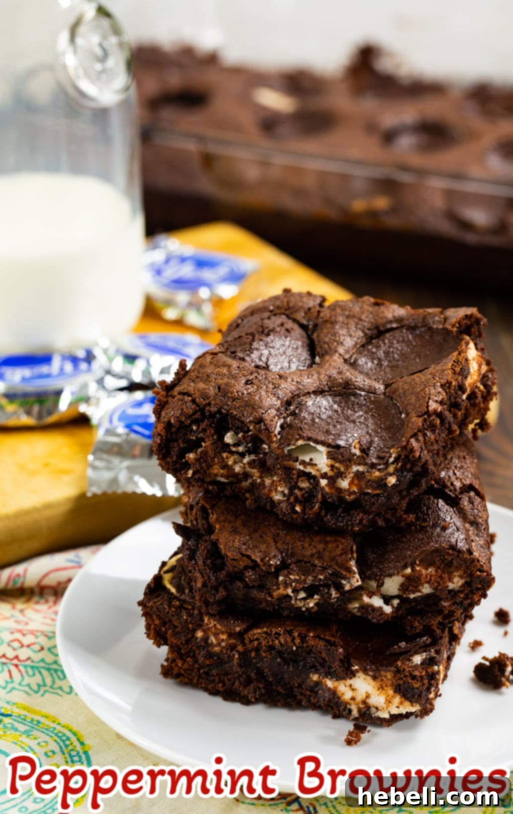 Several peppermint brownies stacked on a white plate, ready to be served.