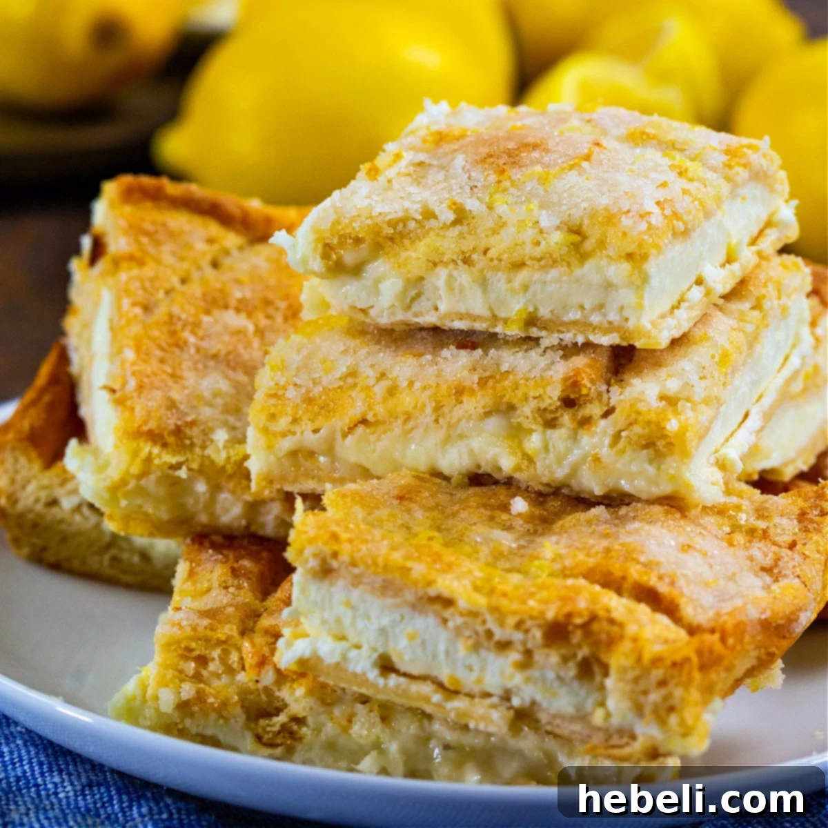 Zesty Lemon Cream Cheese Bars 2 Stacked Lemon Cream Cheese Bars on a pristine white plate, garnished with fresh lemon zest.