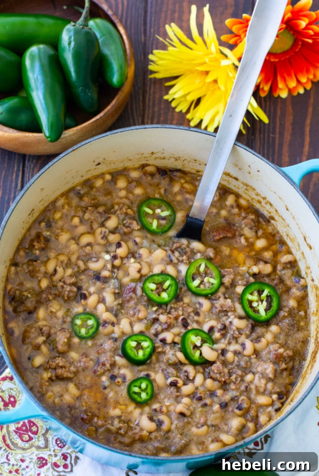 Zesty Black-Eyed Peas 3 A spoon scooping up a generous portion of Black-Eyed Peas with Jalapeno, showing the creamy texture and bits of sausage.