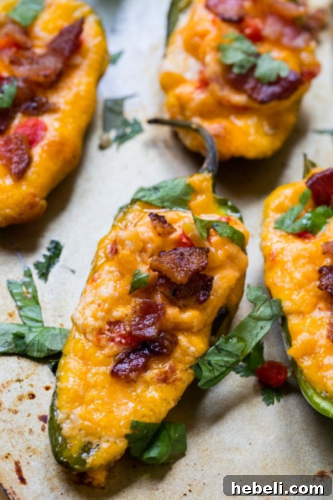 Spicy Pimento Cheese Poppers 4 Pimento Cheese Stuffed Jalapenos with bacon and cilantro garnish.
