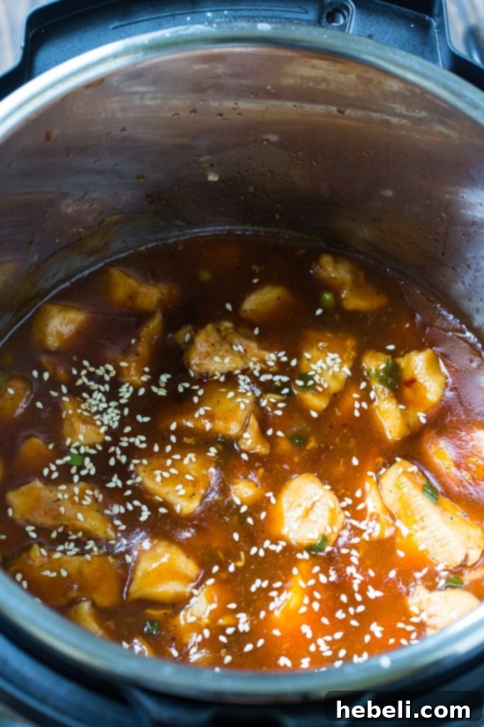 Close-up shot of tender, bite-sized chicken pieces coated in a glossy honey sesame sauce, highlighting the texture and richness of the dish.
