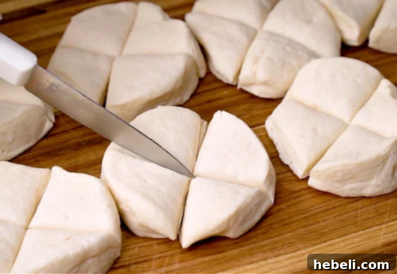 Hands cutting refrigerated biscuits into fourths on a cutting board, ready for the casserole.