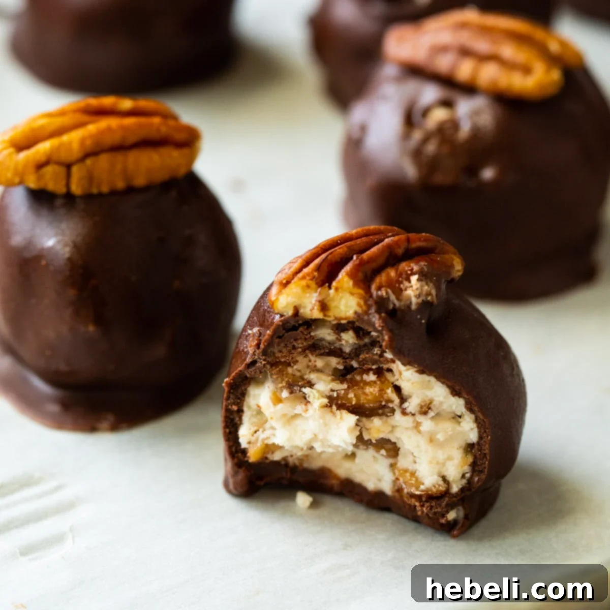 Bourbon Balls covered in chocolate and topped with pecan halves.