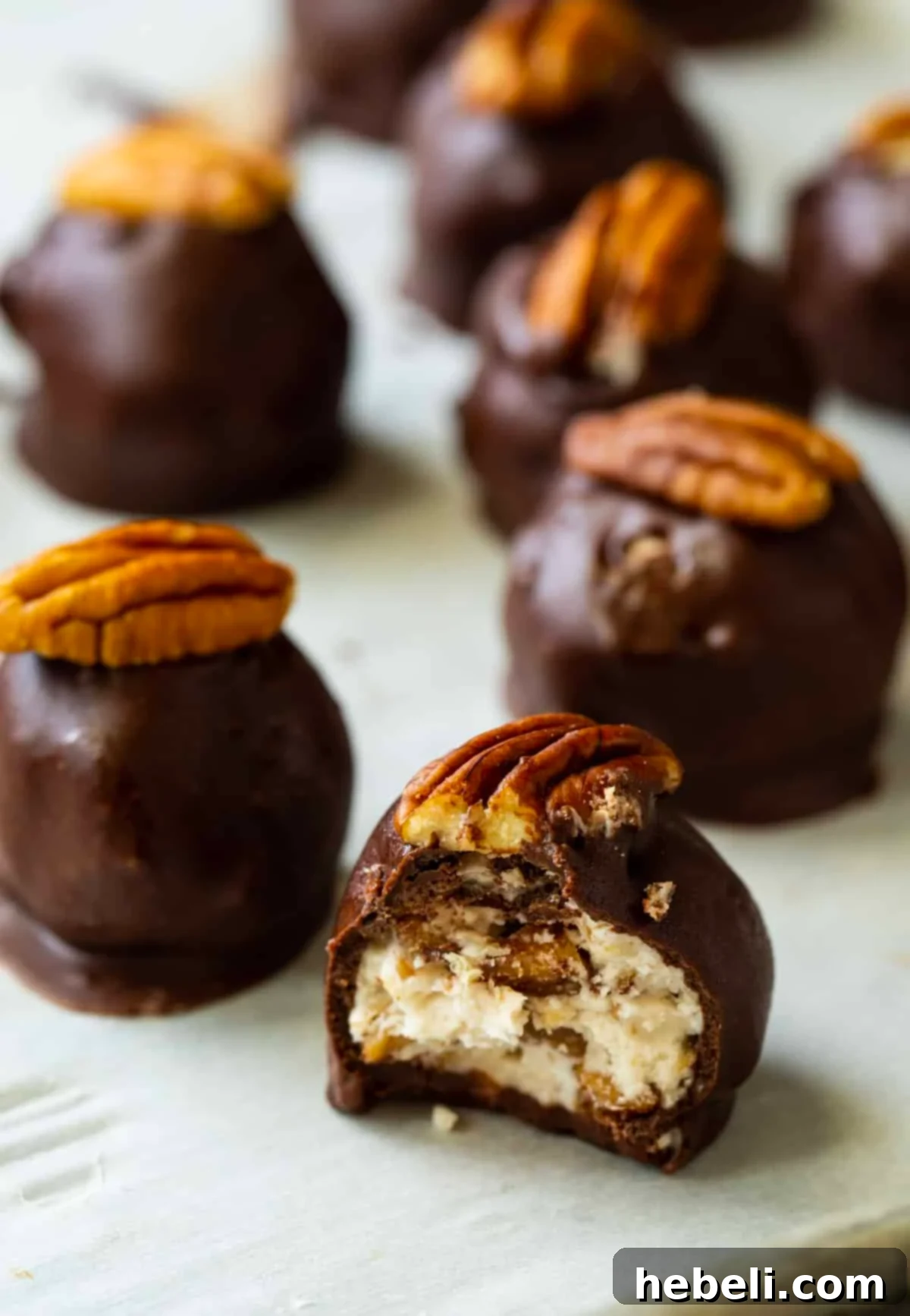 Bourbon Ball with a bite taken out, revealing the pecan and bourbon-infused interior.