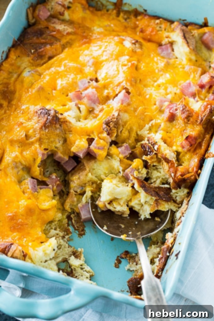 Savory Croissant Ham and Cheese Bake 5 A slice of Ham and Cheese Croissant Casserole on a plate with fresh herbs