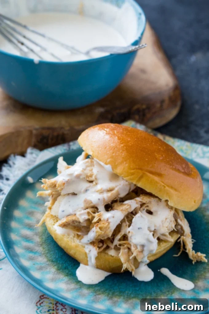 Slow Cooker Alabama White Pulled Chicken 3 Homemade Alabama White BBQ Sauce in a glass bowl with a whisk
