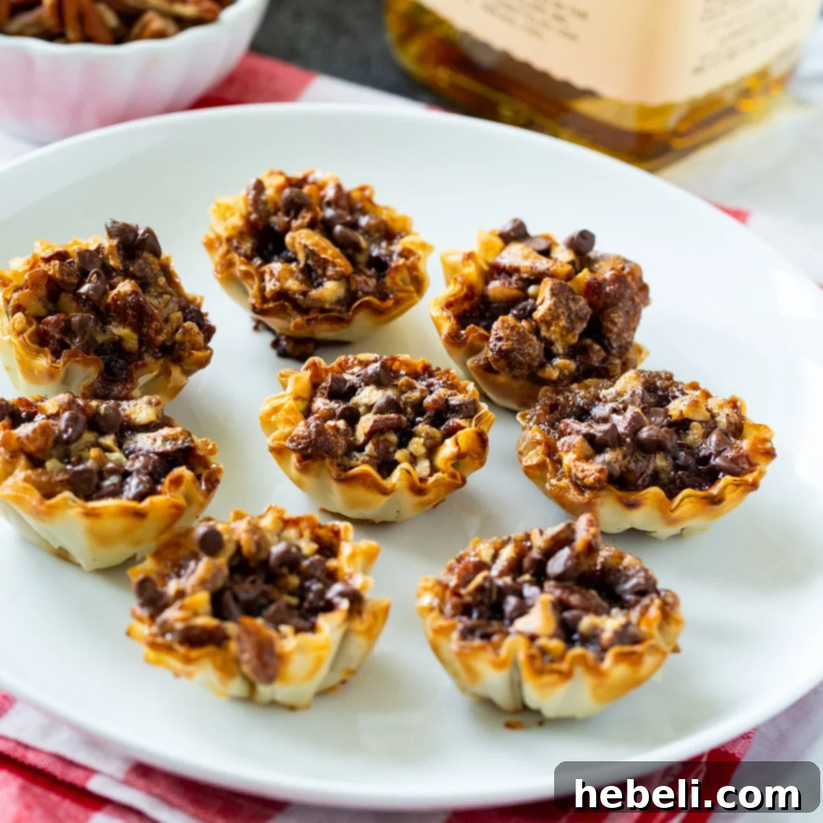 Whiskey-Kissed Pecan Mini Pies 2 A plate of golden-brown Bourbon Pecan Tartlets, showcasing their delectable filling and flaky crust.