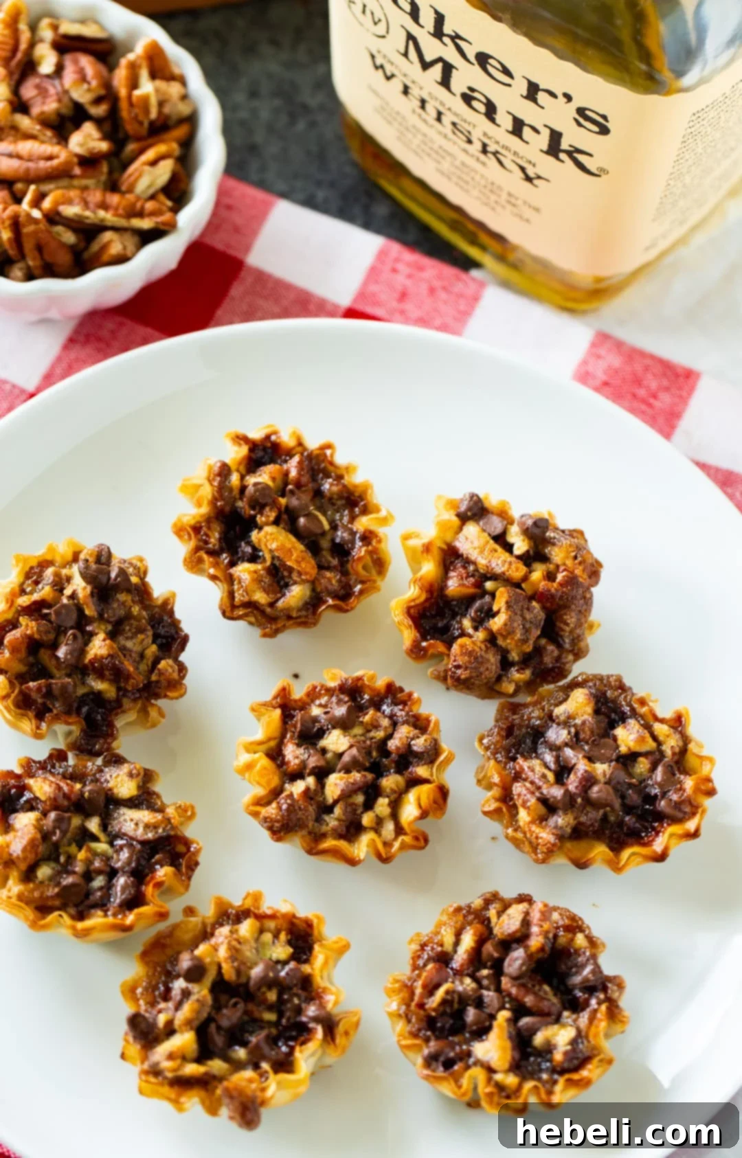 Whiskey-Kissed Pecan Mini Pies 3 An overhead shot of several Bourbon Pecan Tartlets neatly arranged on a white plate, highlighting their golden crusts and rich fillings.