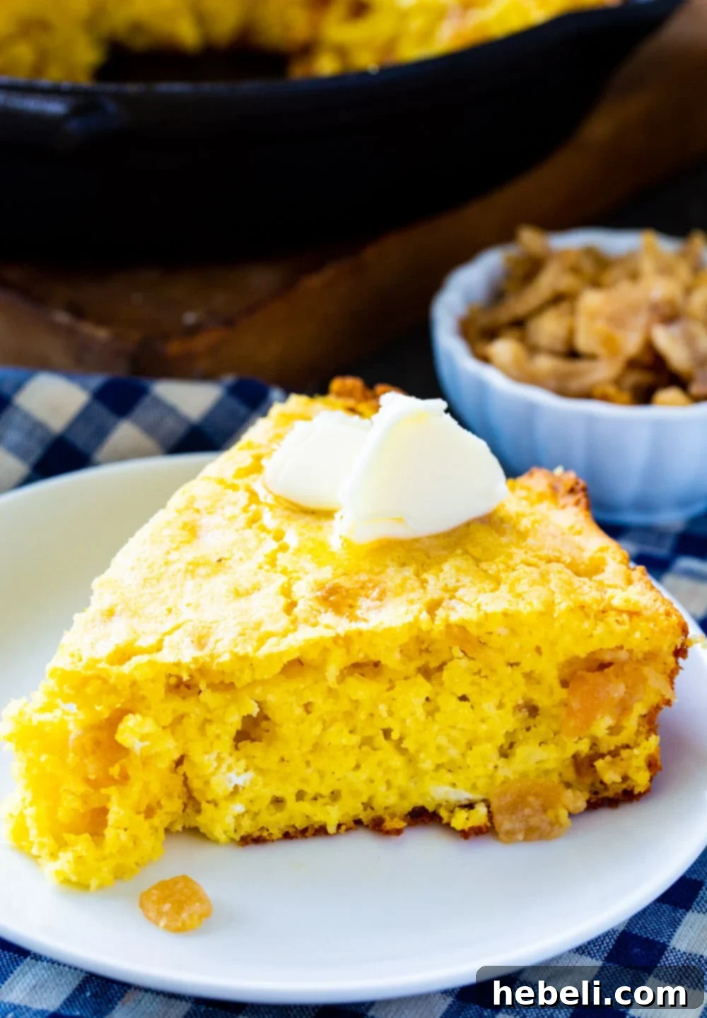 A hearty portion of homemade cornbread studded with flavorful pork cracklings, presented beautifully on a rustic white plate, ready to be enjoyed.