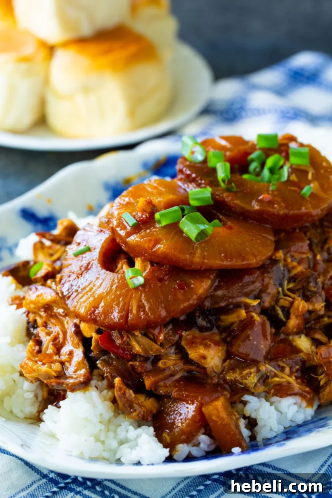 Tropical Sticky Slow Cooker Chicken 4 A serving of Hawaiian Chicken with rice and whole pineapple rings, garnished with fresh green onions.