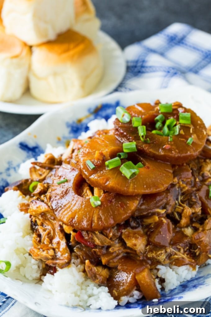 Tropical Sticky Slow Cooker Chicken 5 A bowl of Crock Pot Sticky Hawaiian Chicken with a side of King's Hawaiian Rolls.