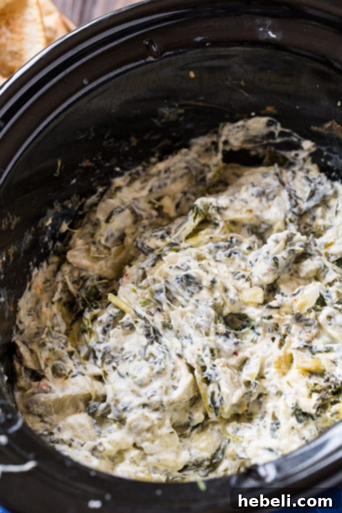 Showstopping Party Dips 4 A bubbling crock pot of creamy spinach artichoke dip, served with various dippers.