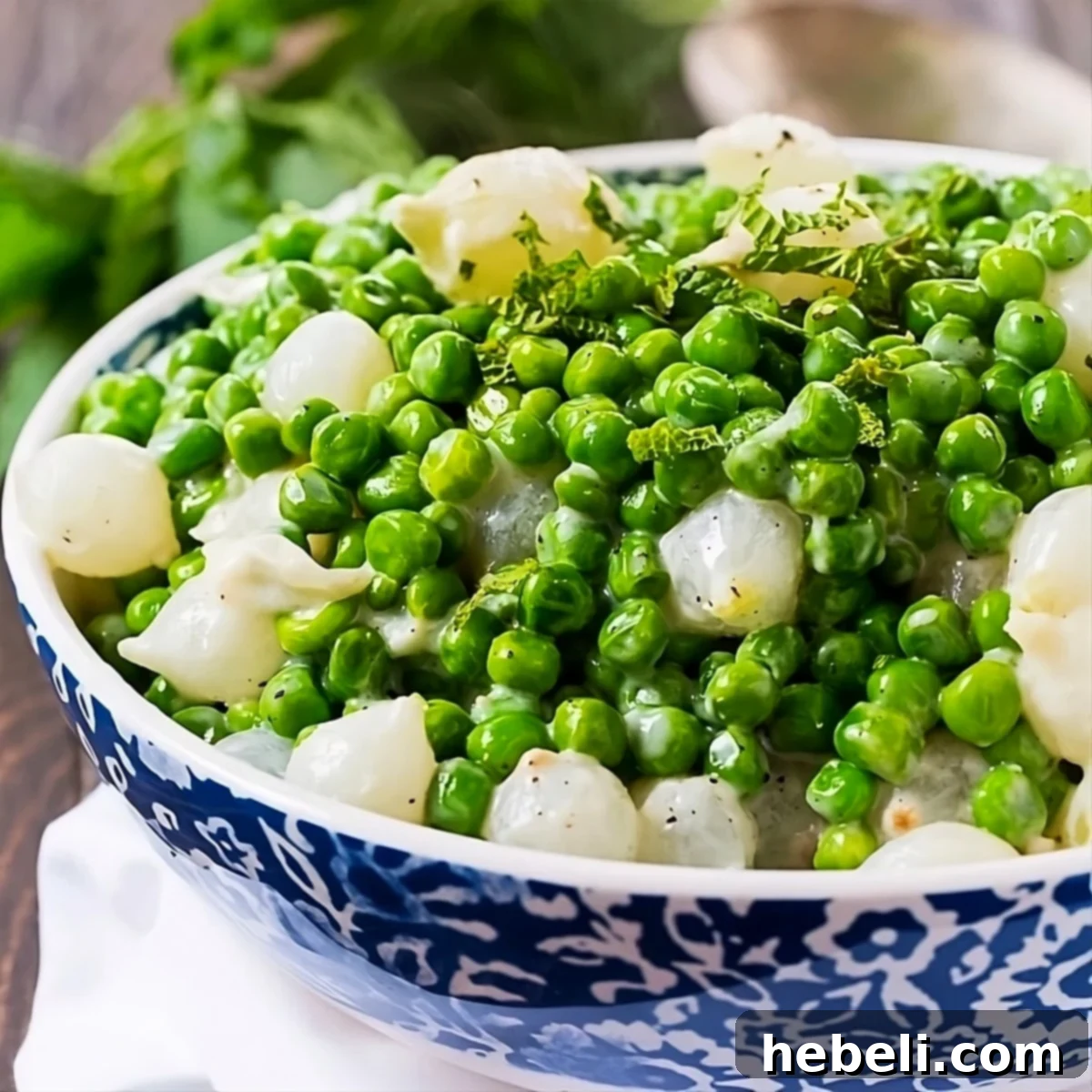 Creamed Peas and Pearl Onions in a serving bowl, garnished with fresh mint.