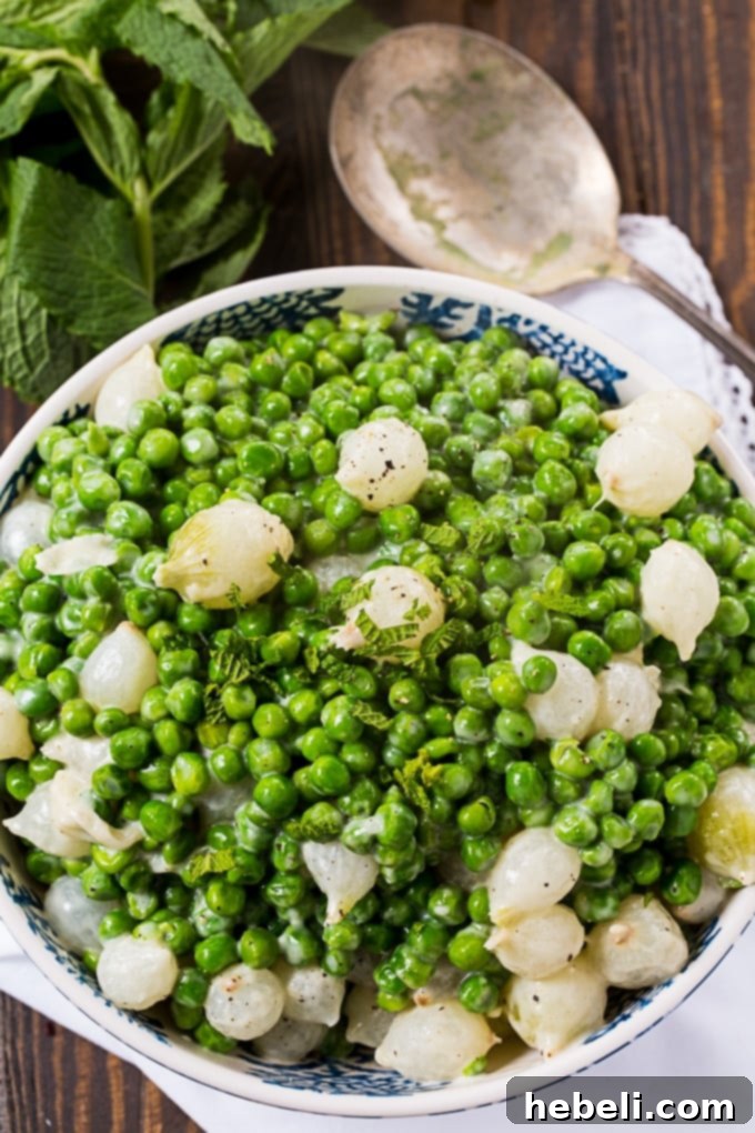 Close-up of Creamed Peas and Pearl Onions in a skillet, mid-cooking process.