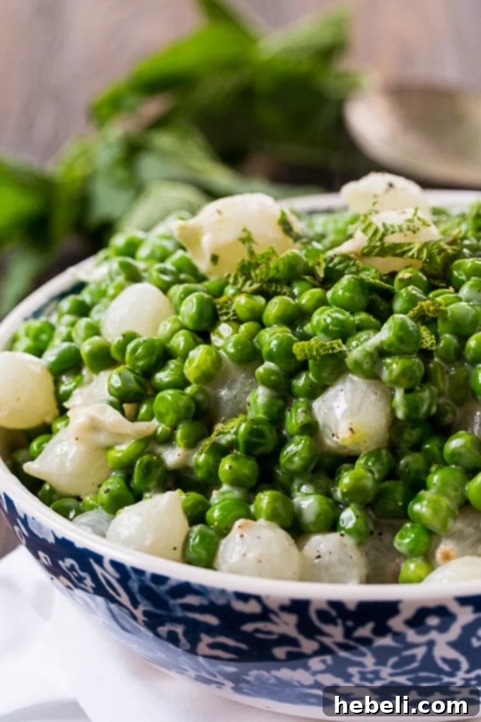 A bowl of Creamed Peas and Pearl Onions ready to be served, with a spoon.