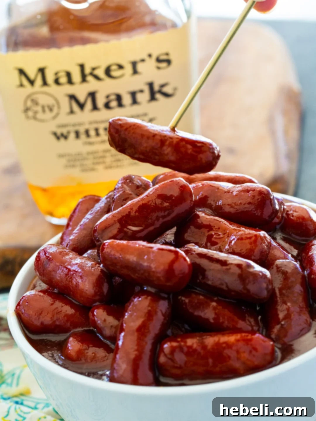 Sticky Bourbon Smokies 3 A single Bourbon Smokie speared with a toothpick, showcasing its glossy, savory coating.