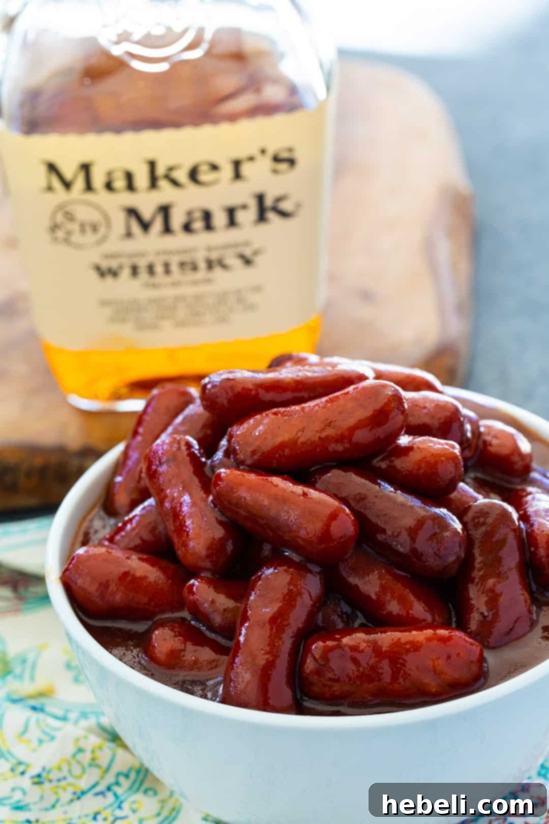 Sticky Bourbon Smokies 5 Crock Pot Bourbon Smokies served in a rustic bowl next to a bottle of bourbon, highlighting the key ingredient.