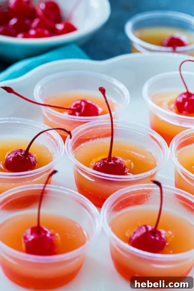 Caramelized Pineapple Cake Jell-O Shots 3 Close-up of layered Pineapple Upside Down Cake Jello Shots with maraschino cherries on top