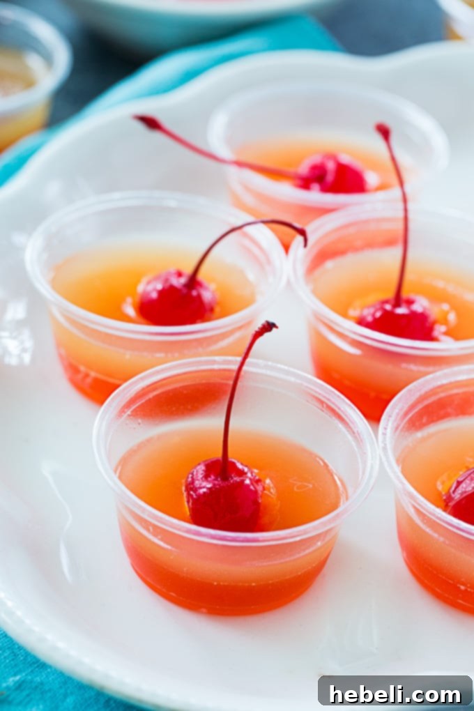 Caramelized Pineapple Cake Jell-O Shots 5 Neatly arranged Pineapple Upside Down Cake Jello Shots in clear plastic cups, showcasing the vibrant colors.
