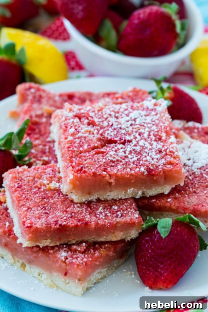 Zesty Strawberry Lemonade Bars 4 Several Strawberry Lemonade Bars arranged neatly on a plate, dusted with powdered sugar.