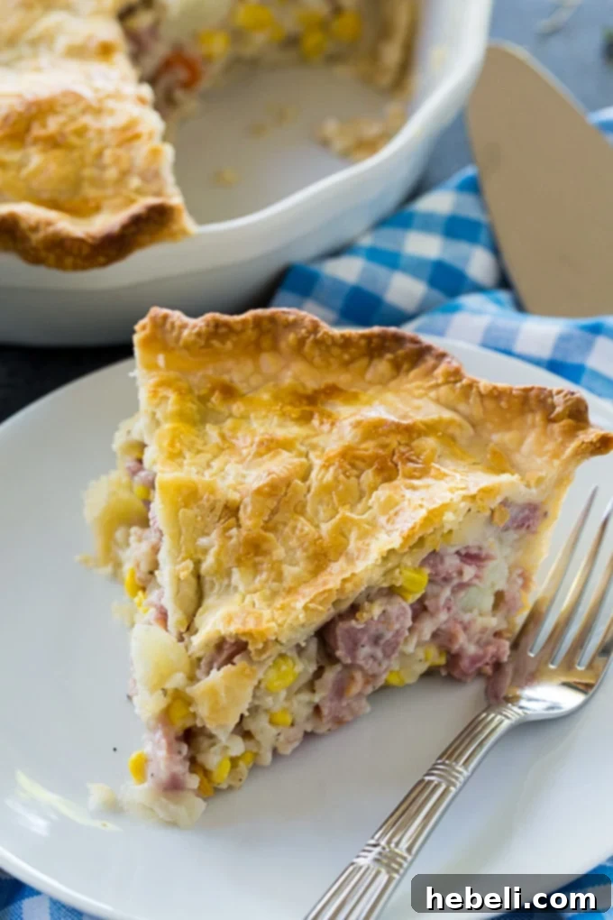 A slice of Ham Pot Pie on a white plate, showcasing the rich filling and flaky crust