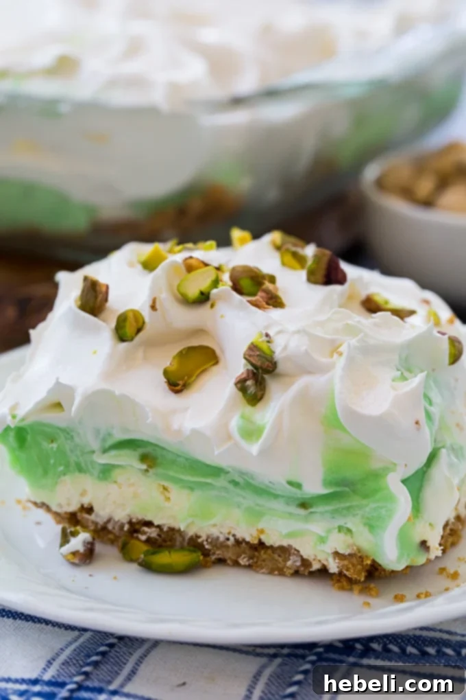 Pistachio Lush dessert showing distinct layers of graham cracker crust, cream cheese, pistachio pudding, and whipped topping