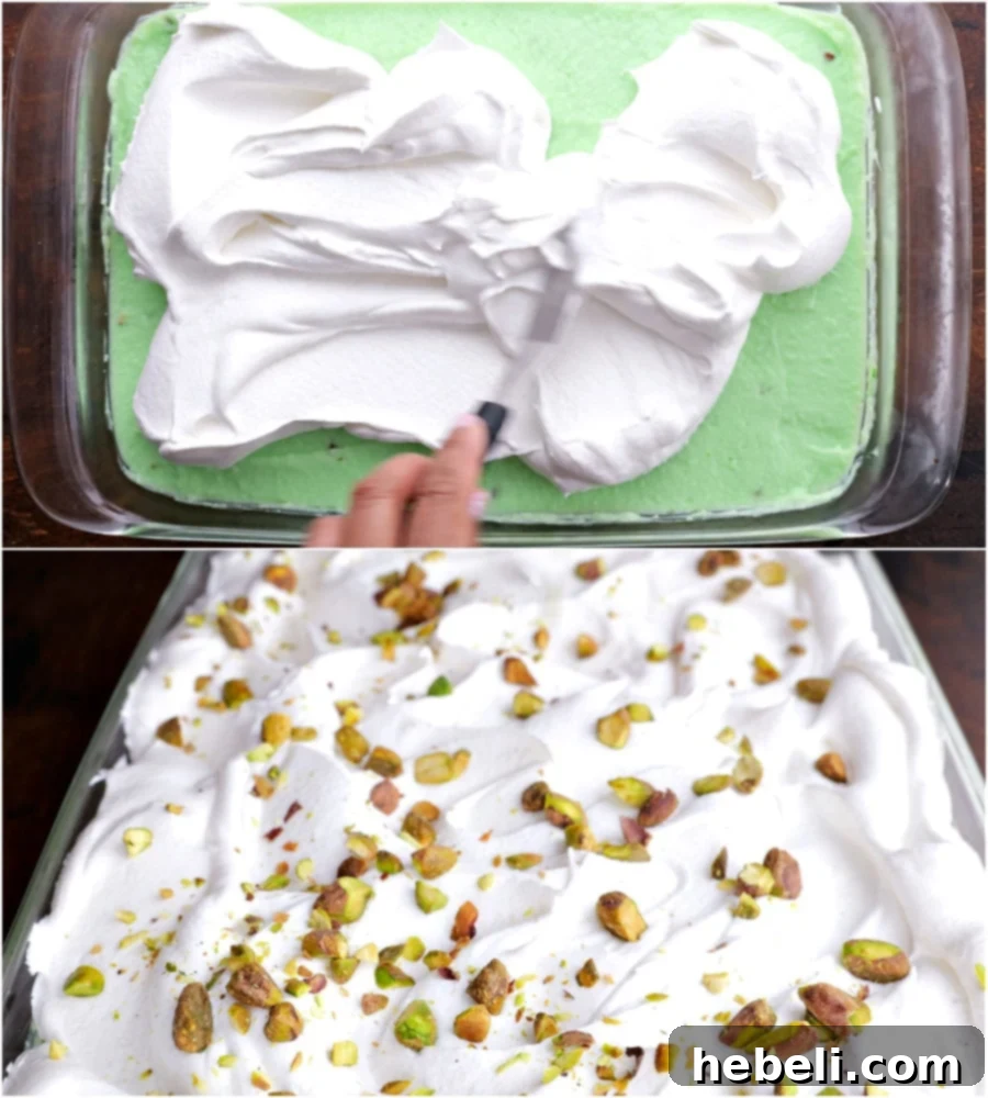 Spreading Cool Whip on top of the pistachio pudding layer for the final topping