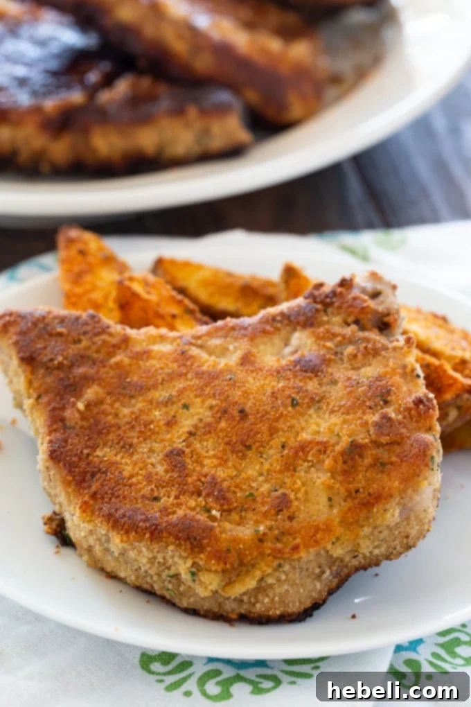 Close-up of crispy Ranch Seasoned Fried Pork Chops on a cutting board, garnished with fresh herbs, highlighting the crunchy golden-brown texture